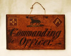 wooden Commanding Officer sign with Royal West Surrey lamb insignia painted at the top.