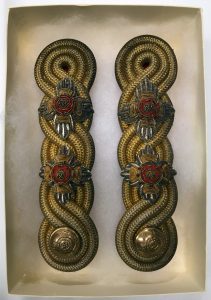 Two gold braided epaulettes featuring fabric lieutenant insignia and one button each.