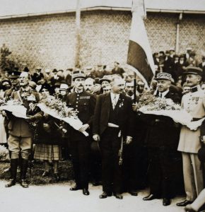 black and white photograph of a group of men, some in military dress, several holding flowers.