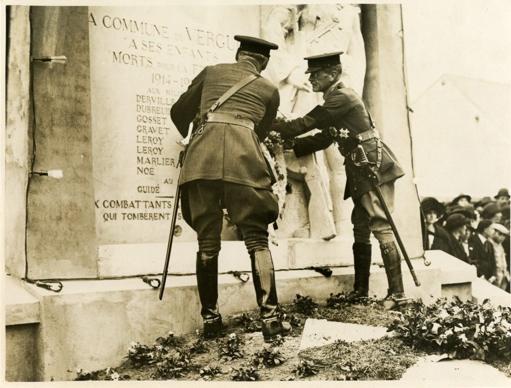 Two British military officers from WWI placing a wreath on a war memorial in the French village of Le Verguier.