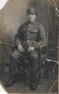 Sepia, full-length photo of seated WWI soldier from the British Army, The Queen's (Royal West Surrey) Regiment